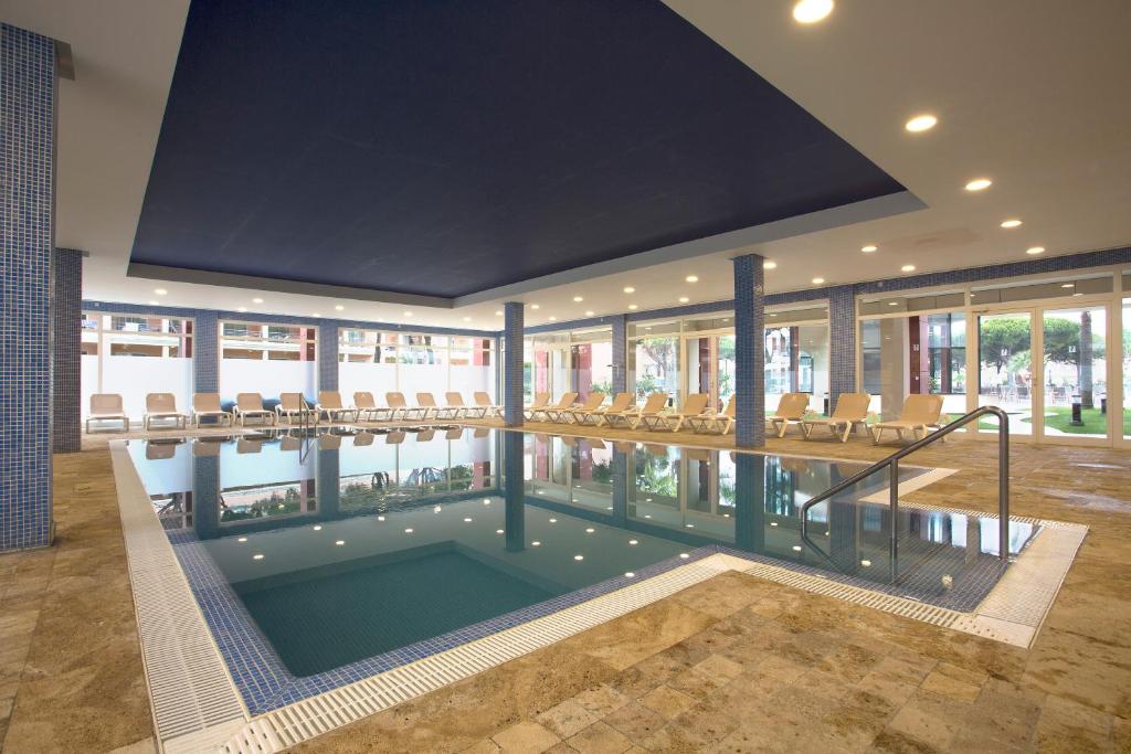 a swimming pool in a building with chairs around it at Hipotels Barrosa Garden in Chiclana de la Frontera