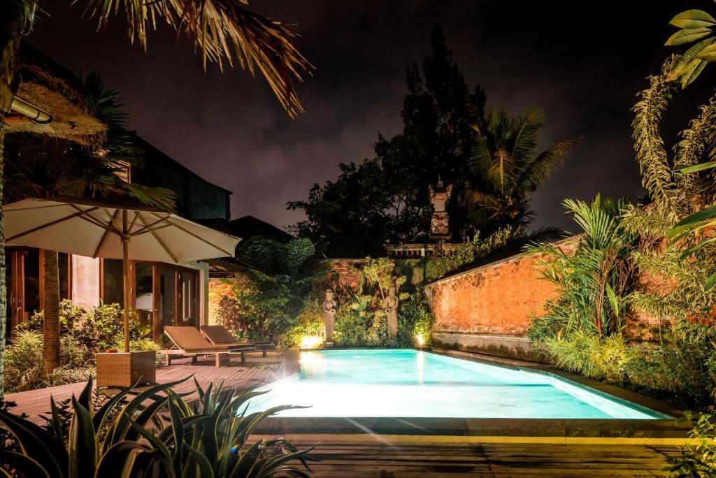 a swimming pool in a yard at night at The Kalangan in Ubud