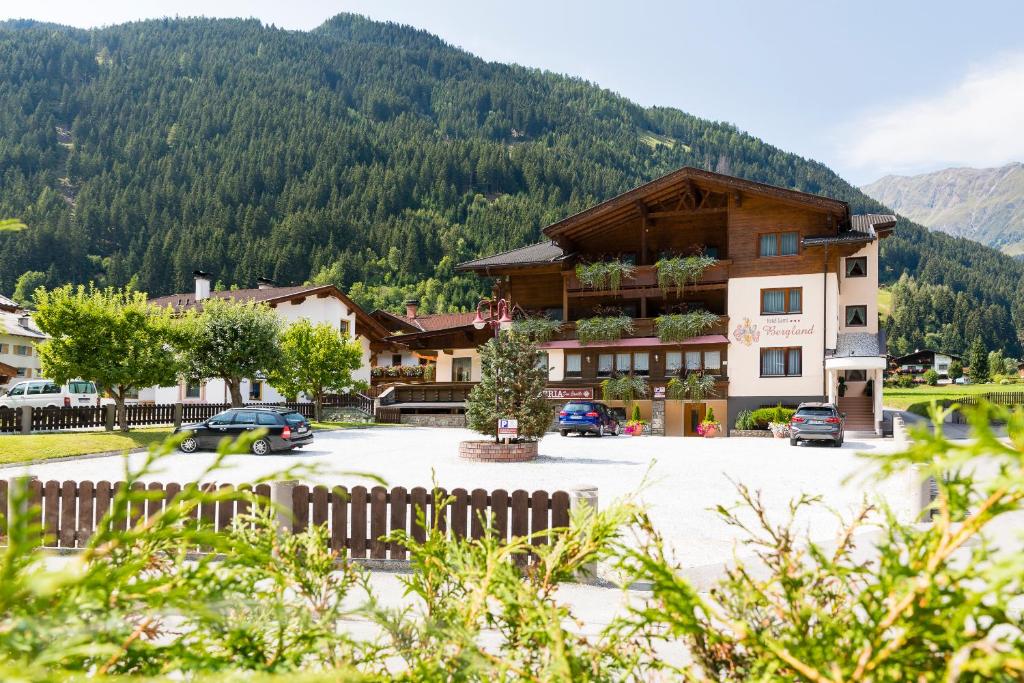 a building with a parking lot in front of a mountain at Hotel Garni Bergland in Neustift im Stubaital
