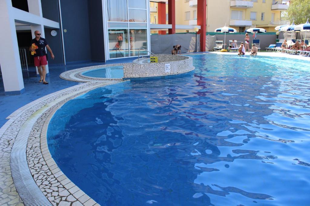 a large pool with blue water in a building at Hotel Ambassador in Caorle