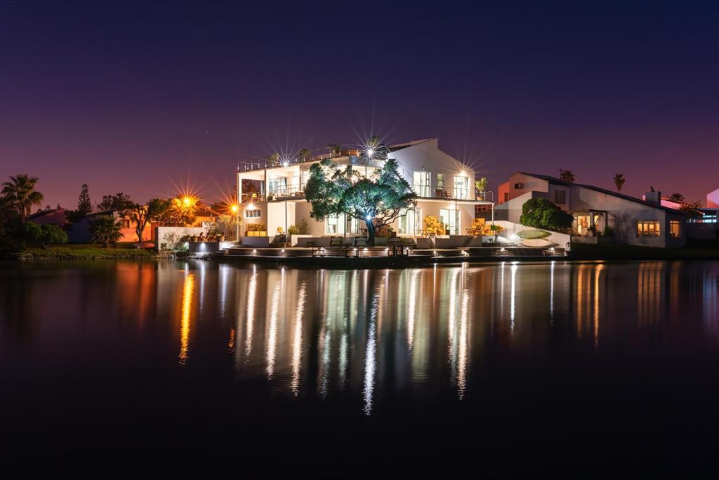 een huis dat 's nachts op het water zit bij Marina Views in Muizenberg