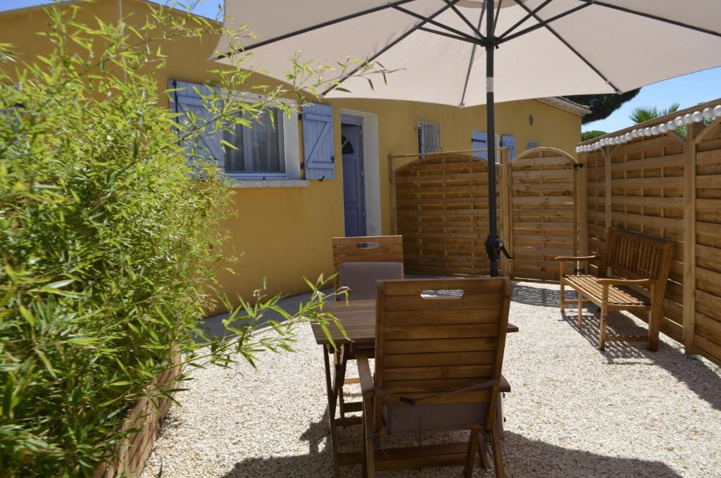 uma mesa e cadeiras com um guarda-sol num jardim em Sun and cosy em Vias