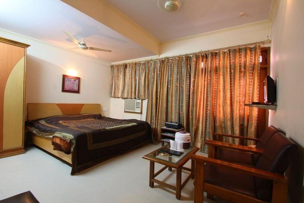 a bedroom with a bed and a chair and a table at Hotel Sweet Dream in Jaipur