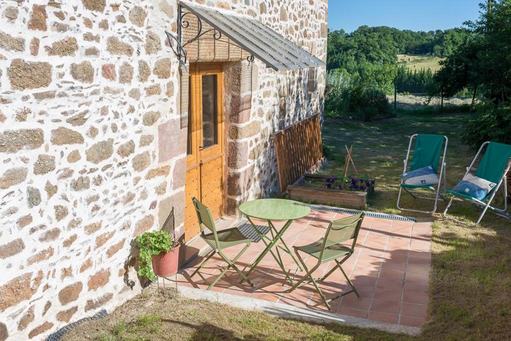 un patio con sillas, una mesa y un edificio en Les Granges De Cassard en Anglars