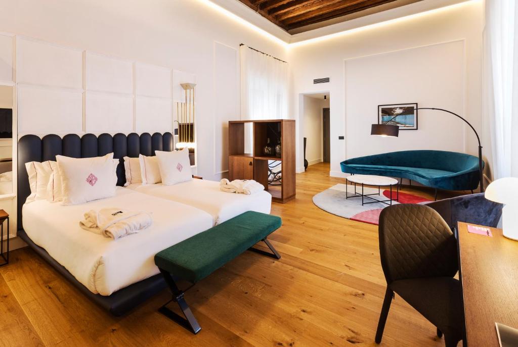 Quarto moderno do One Shot Conde Torrejón com sofá de veludo verde, mesa de centro de mármore e luminária de piso com abajur escuro em ambiente amplo e iluminado, para representar hotéis em Sevilha.