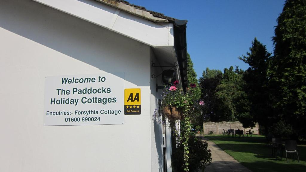 una señal en el lado de un edificio blanco con una casa en The Paddocks Cottages en Symonds Yat