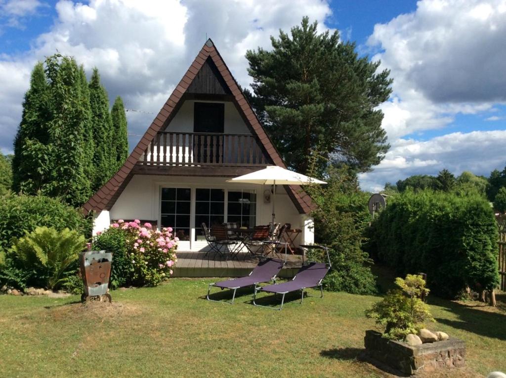 une maison avec deux chaises et un parasol dans la cour dans l'établissement Ferienhaus Kerstin, à Lindow