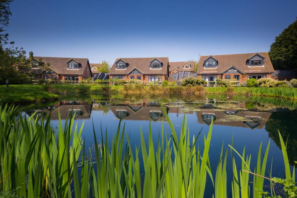 uma fila de casas refletidas num lago em The Lakes Rookley em Rookley