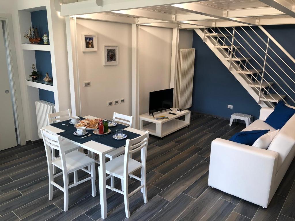 a living room with a table and chairs and a staircase at Splendido Loft al mare in Martinsicuro