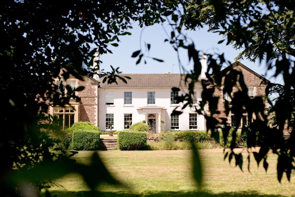 una grande casa bianca con alberi di fronte di Glewstone Court Country House Hotel a Ross on Wye