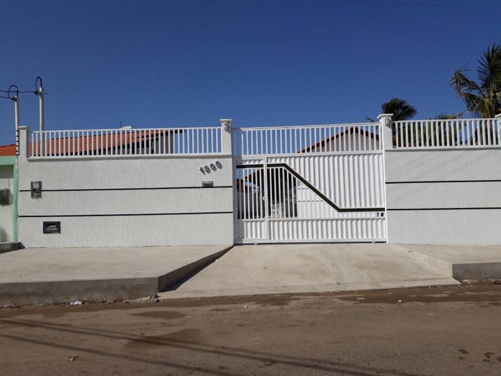 a white fence with a gate with a staircase at CONDOMÍNIO VENTO DO LITORAL in Luis Correia