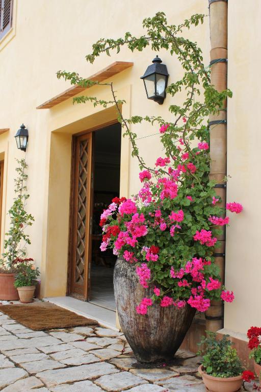 a large planter filled with pink flowers in front of a door at Torre Bennistra in Scopello