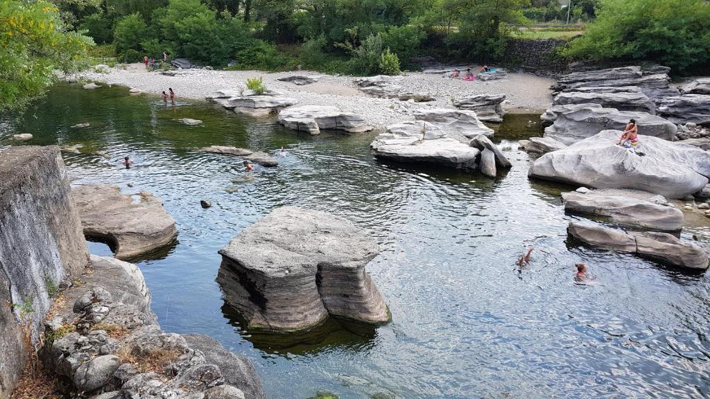 a group of people swimming in a river with rocks at Gite Le Moulin de Rosieres Moulin Champetier in Rosières