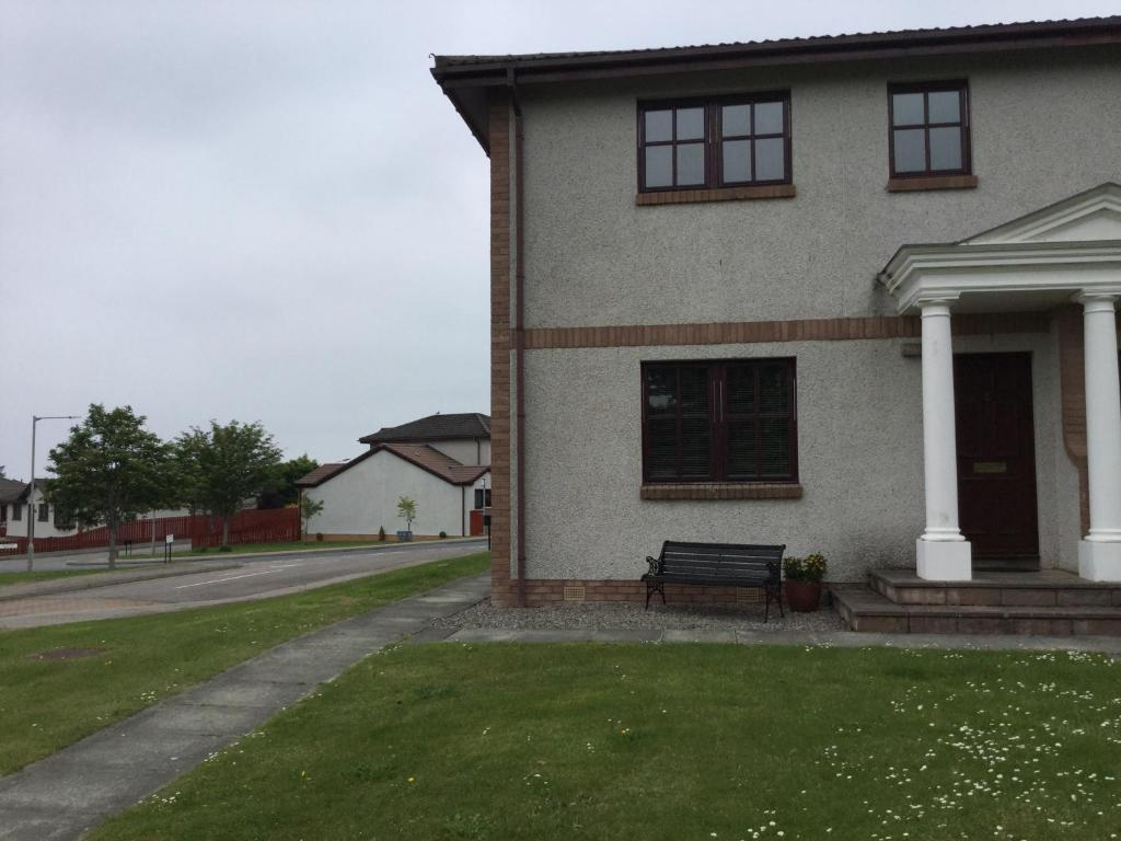 a house with a bench in the front yard at Two Bedroom Glen View Free Parking in Inverness