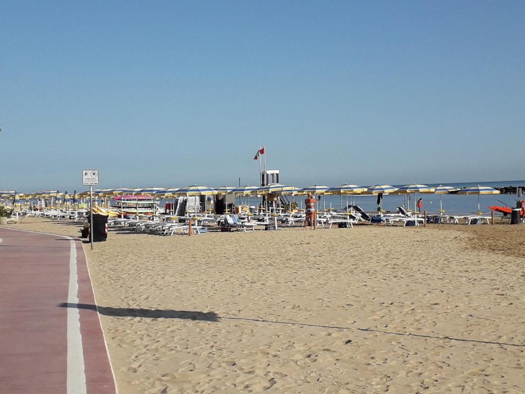 una spiaggia sabbiosa con sedie e ombrelloni di Livi Patrik a Fano