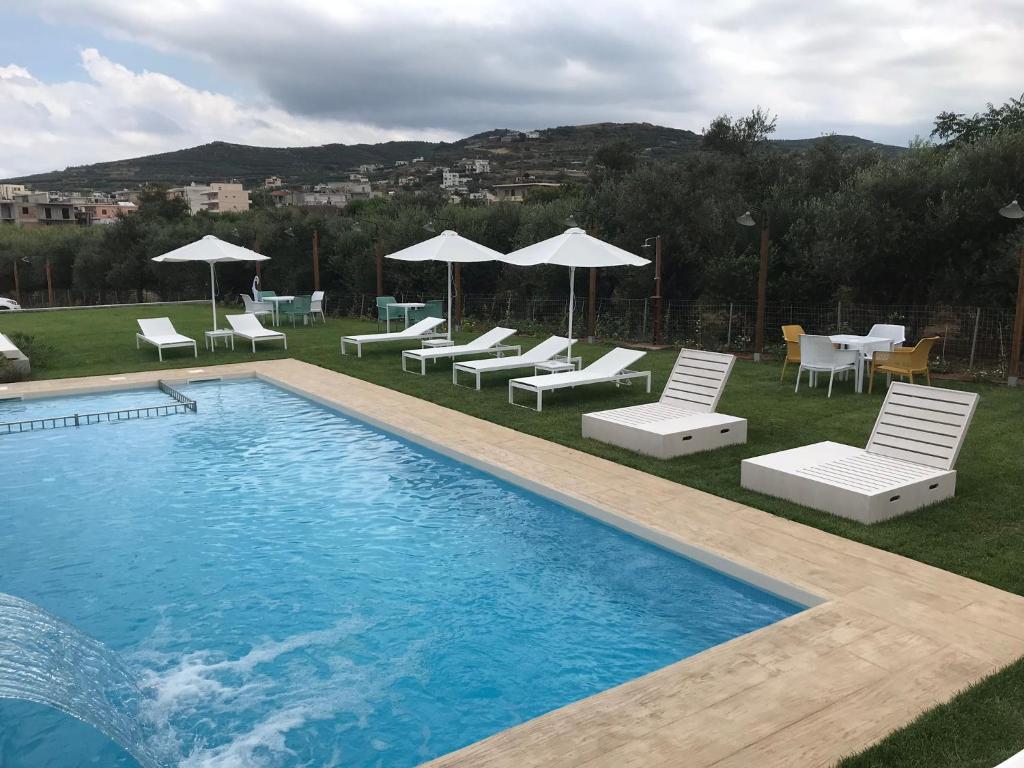 a swimming pool with chairs and tables and umbrellas at Kallimento in Kissamos