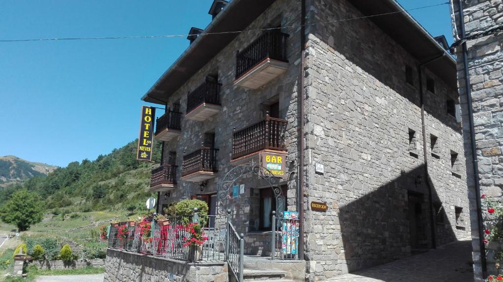un gran edificio de piedra con balcones. en Hotel Las Nieves en Linás de Broto
