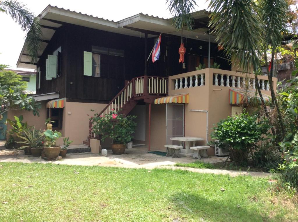 a house with a balcony and a table in the yard at Orchid Guest House in Trat