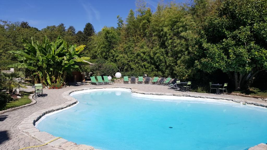 uma grande piscina com cadeiras verdes e árvores em Au Faisan Doré em Neuville-sur-Ain