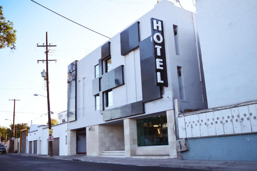 a white building with a black sign on it at Hotel Ht Ole in Tijuana