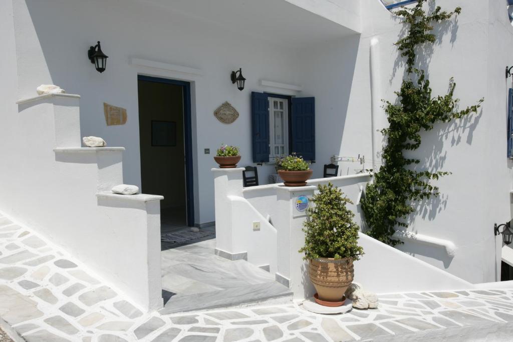 un couloir avec des murs blancs et des plantes en pot dans l'établissement Studios Eleni I, à Tinos