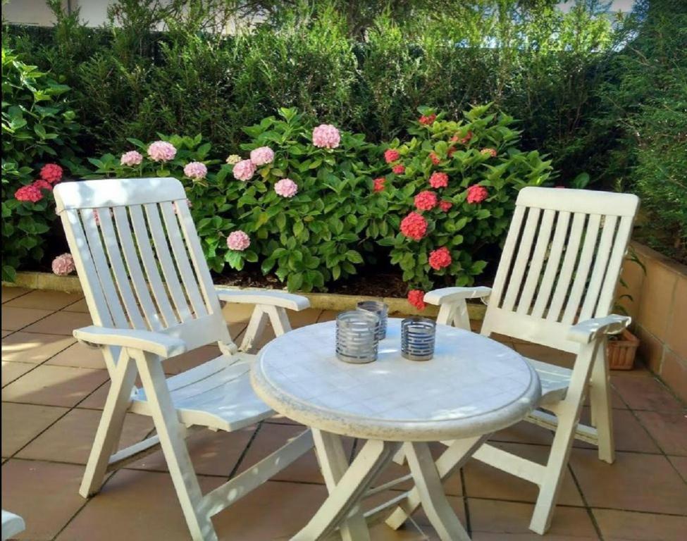 2 Stühle und ein Tisch auf einer Terrasse mit Blumen in der Unterkunft Ondarreta Beach & Terrace in San Sebastián