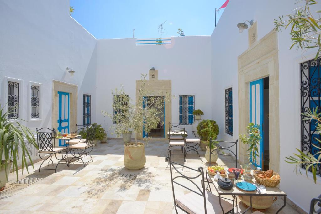 een binnenplaats met tafels en stoelen en een tafel met eten erop bij Dar R'Bat, Maison d'Hôtes de charme in Nabeul