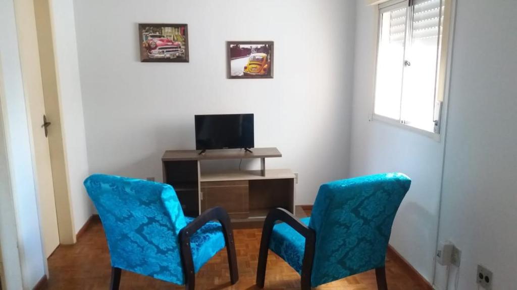 a room with two blue chairs and a television at Vitrine apart. Hotel in Bagé