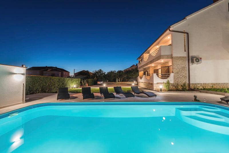 a swimming pool in front of a house at Villa Marivel in Privlaka