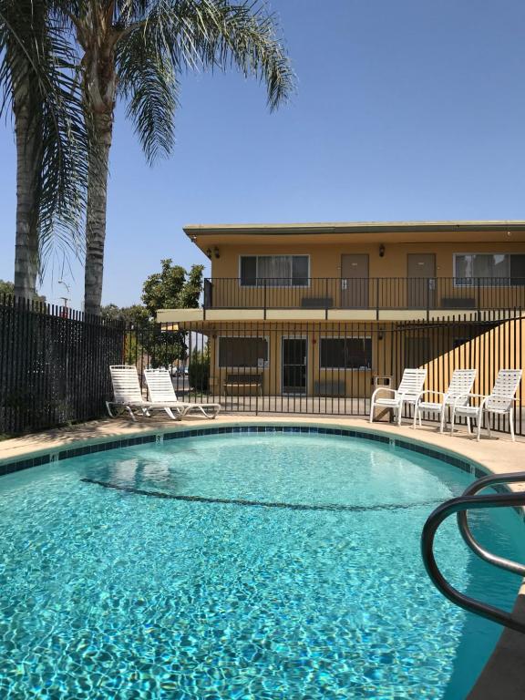 a swimming pool with chairs and a building in the background at Americas Best Value Inn Visalia in Visalia