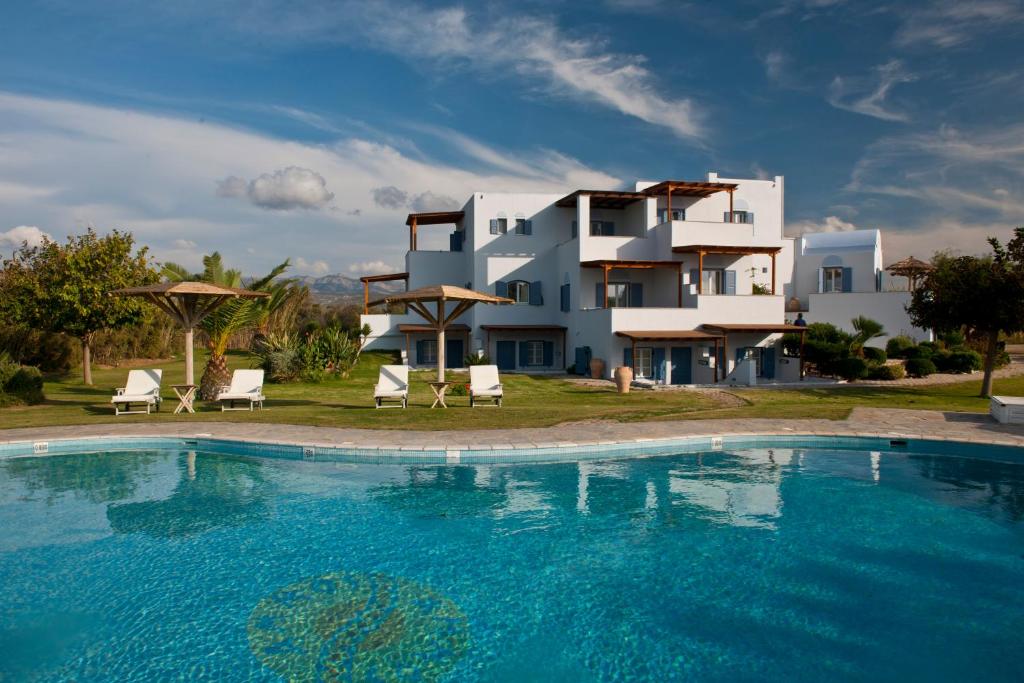 a villa with a swimming pool in front of a house at Ammos Naxos Exclusive Apartments & Studios in Naxos Chora