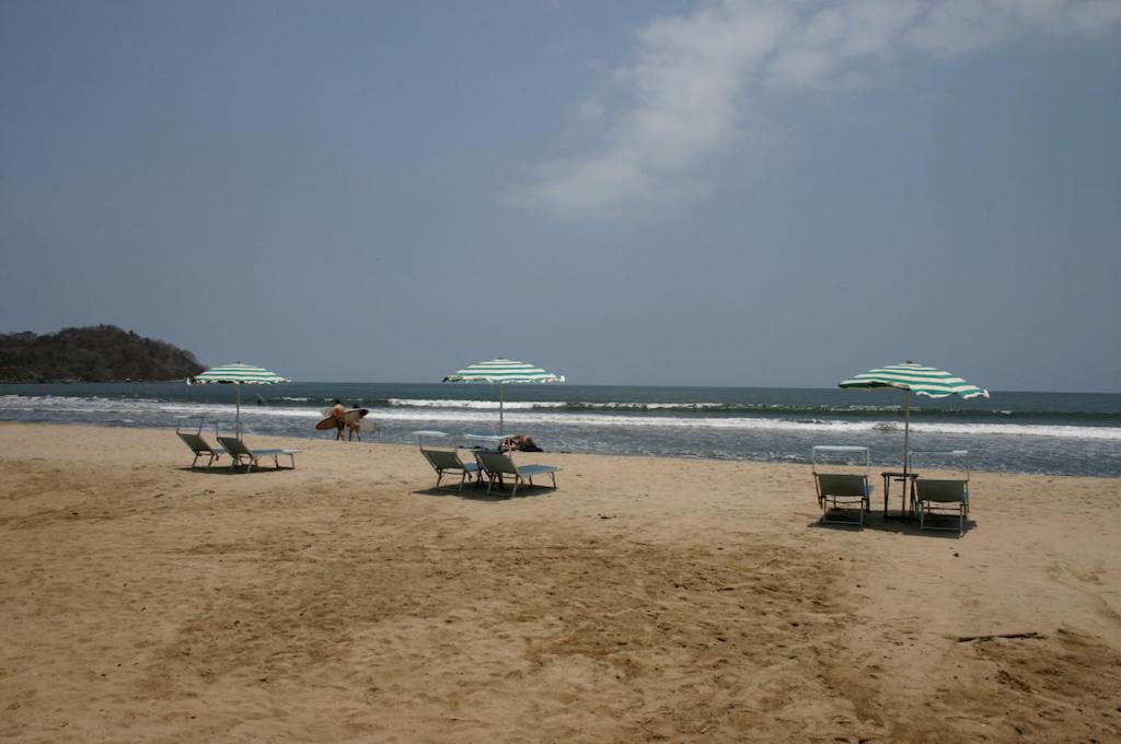 a group of chairs and umbrellas on a beach at Junto al Rio Bungalows & Suites in Sayulita