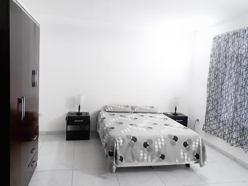 a bedroom with a bed in a white room at City Lodge Apart in Santa Cruz de la Sierra