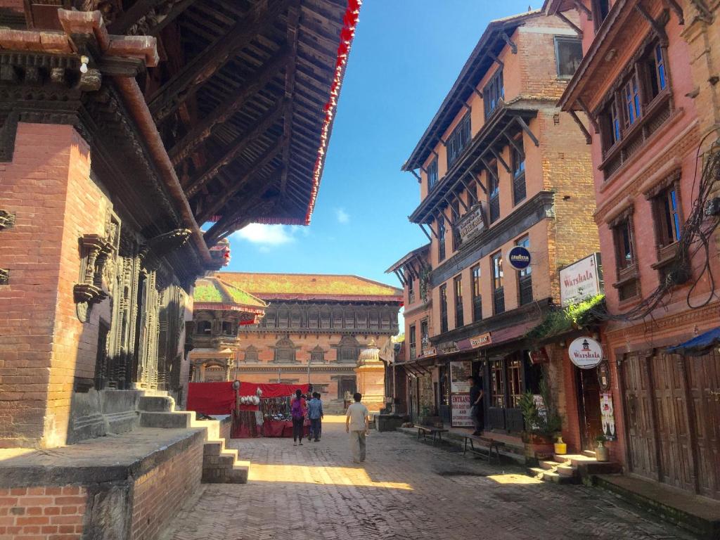 a street with buildings and people walking down a street at Shiva Guest House in Bhaktapur