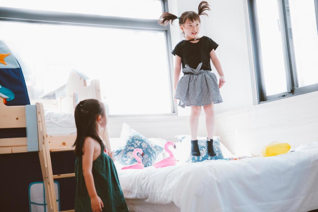 a little girl standing on top of a bed at Meng Yun Ge Hotel in Jiaoxi