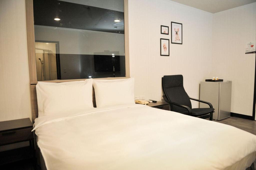 a bedroom with a large white bed and a chair at Huang Kai Hotel in Taichung