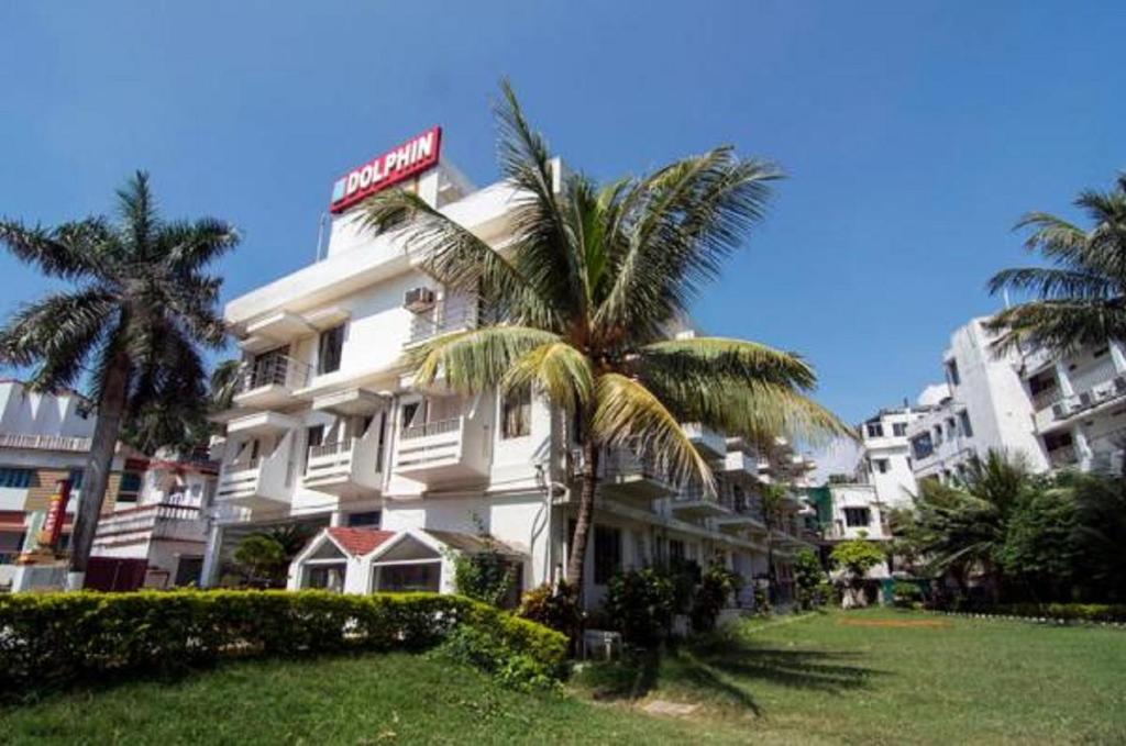 a hotel with a palm tree in front of it at Hotel Dolphin in Digha