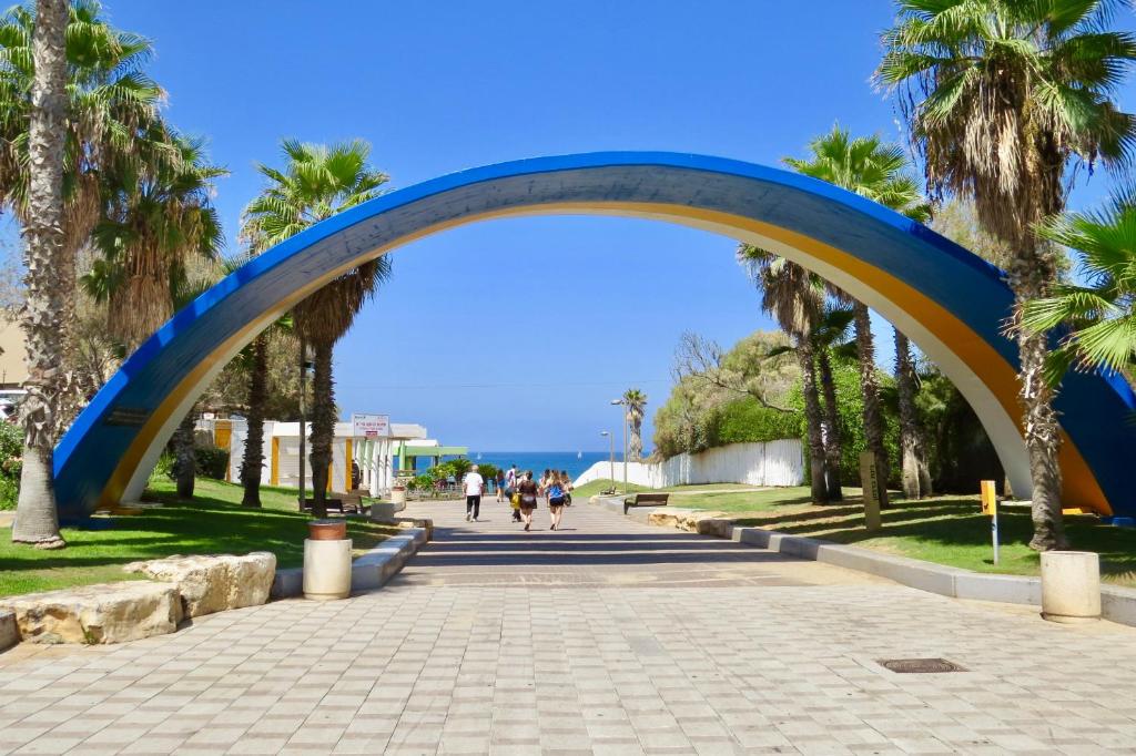 a blue archway over a sidewalk with palm trees at Cozy Studio "De Shalit" in Herzelia 