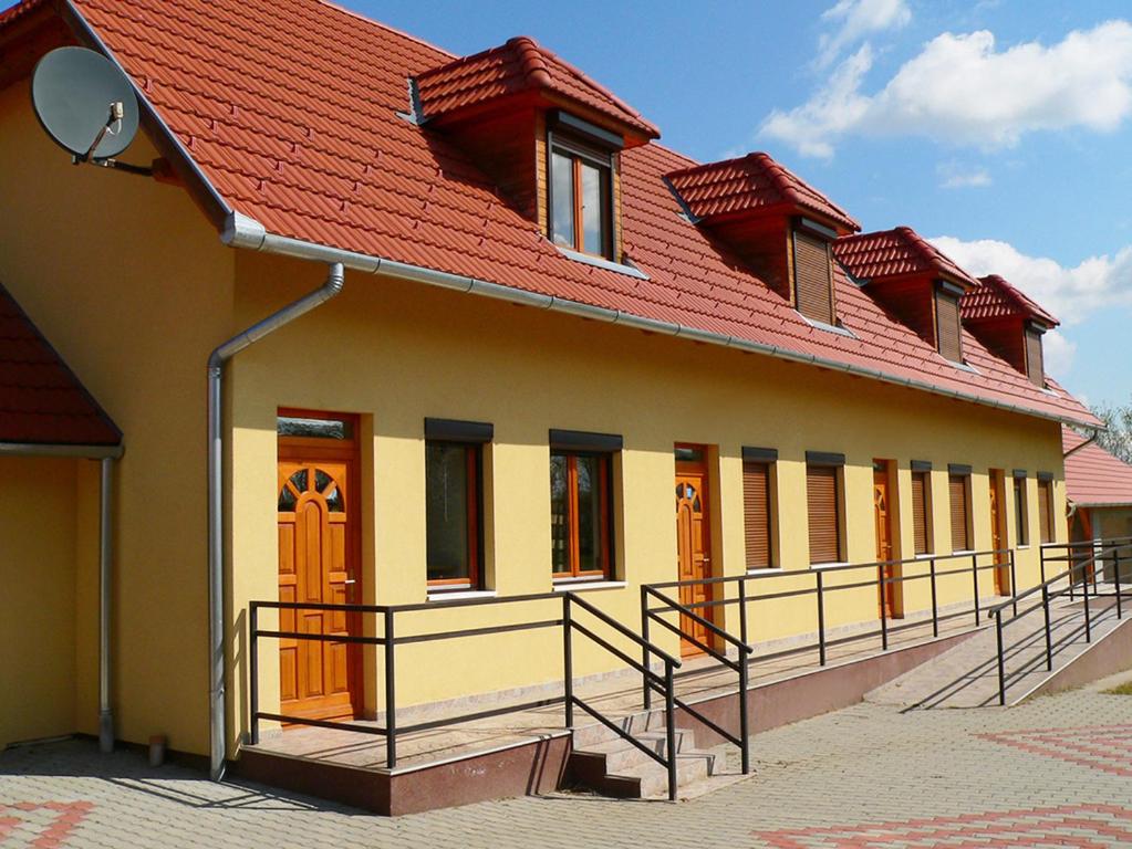 ein Gebäude mit einem roten Dach und einem Balkon in der Unterkunft s'Schnoganeschd in Nemesvid