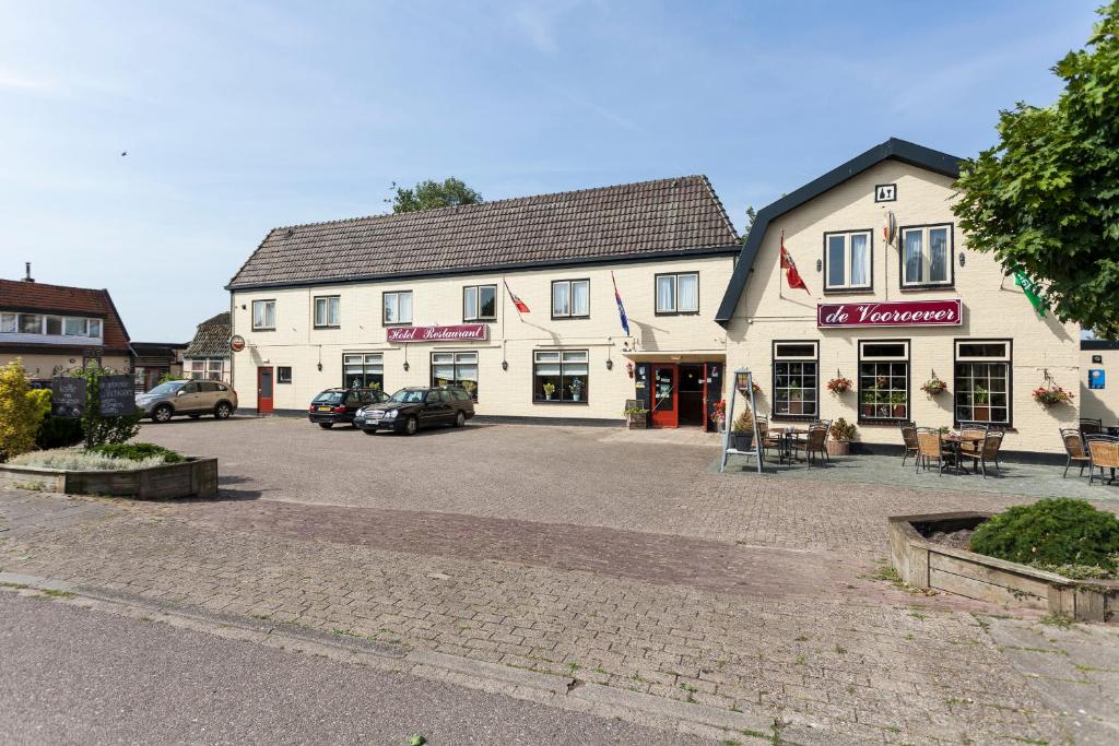 ein großes weißes Gebäude mit Autos auf einem Parkplatz in der Unterkunft De Vooroever in Wervershoof