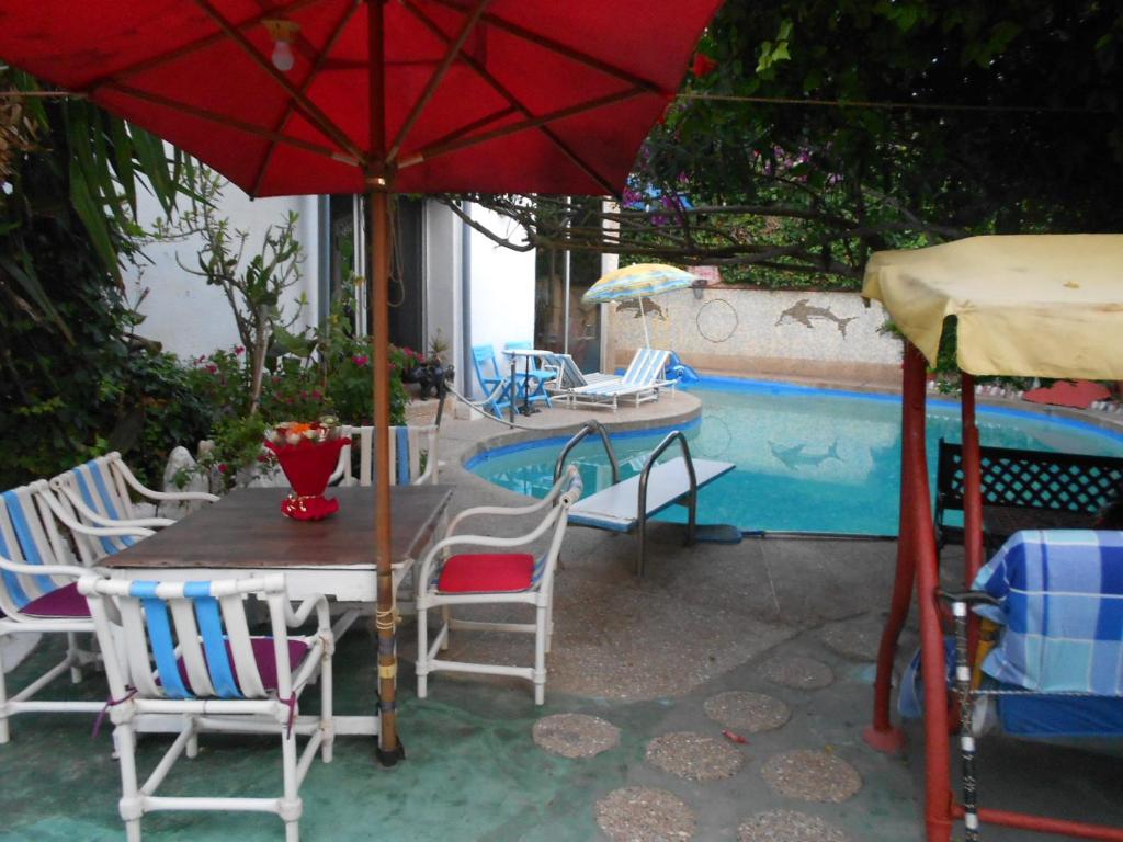 una mesa con sillas y una sombrilla junto a la piscina en Monica plage en Mohammedia