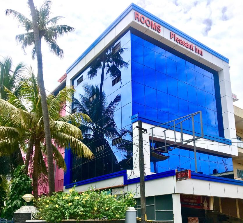 a blue building with palm trees in front of it at Pleasant Inn in Cochin