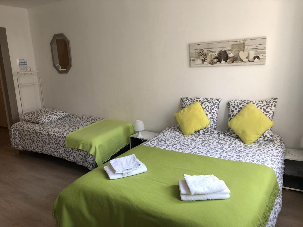 a room with two beds with green sheets and yellow pillows at Le Châtaignier in Forbach