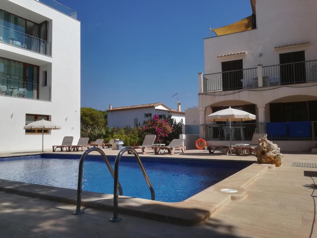 a swimming pool in front of a building at Apartamentos Villa Primera in Cala Figuera