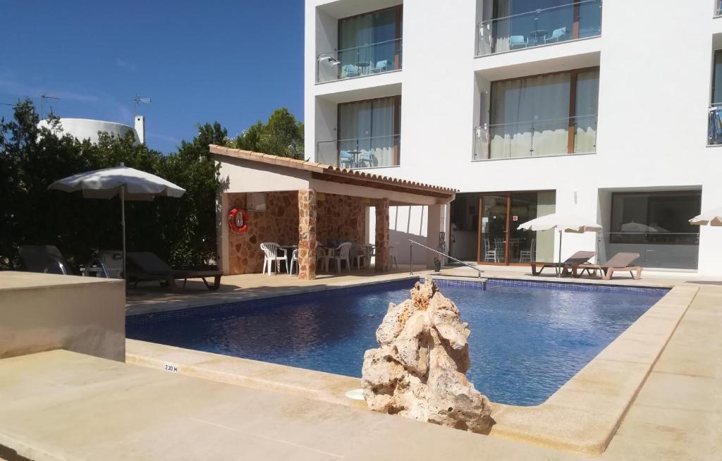 a swimming pool in front of a building at Apartamentos Villa Primera in Cala Figuera
