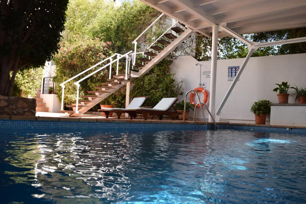 a swimming pool with two chairs and a stairway next to a house at miKasa Agua Amarga & SPA in Agua Amarga
