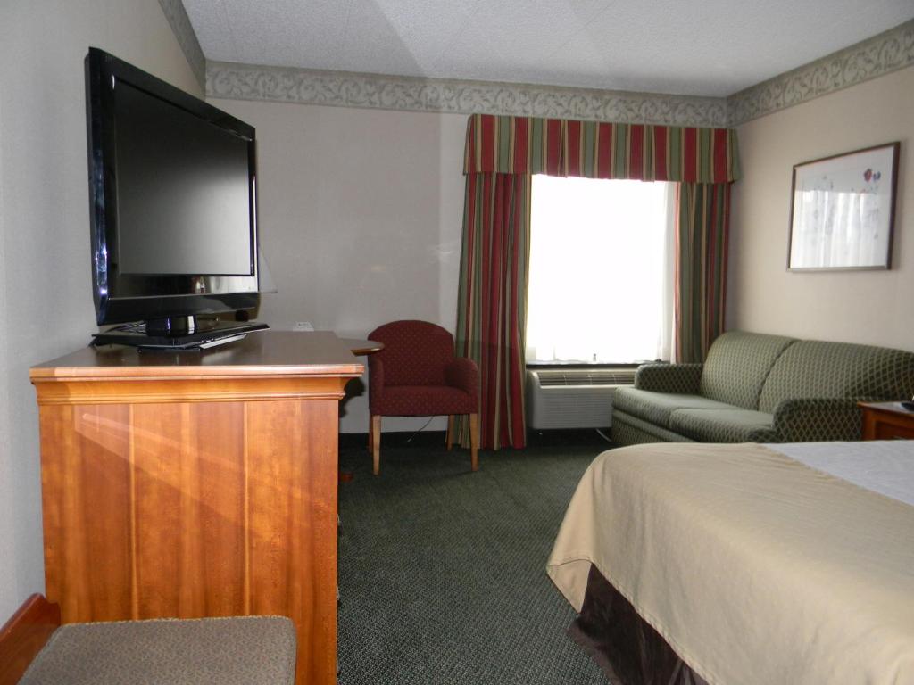 a hotel room with a television and a bed at Holiday Lodge Hotel and Conference Center in Oak Hill