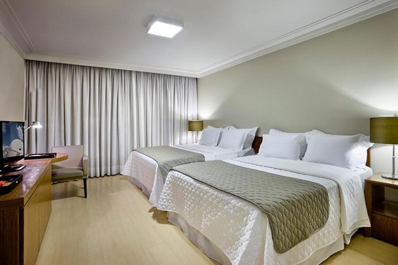 ブラジリアにあるシア パーク エグゼクティブ ホテルのベッド2台とデスクが備わるホテルルームです。