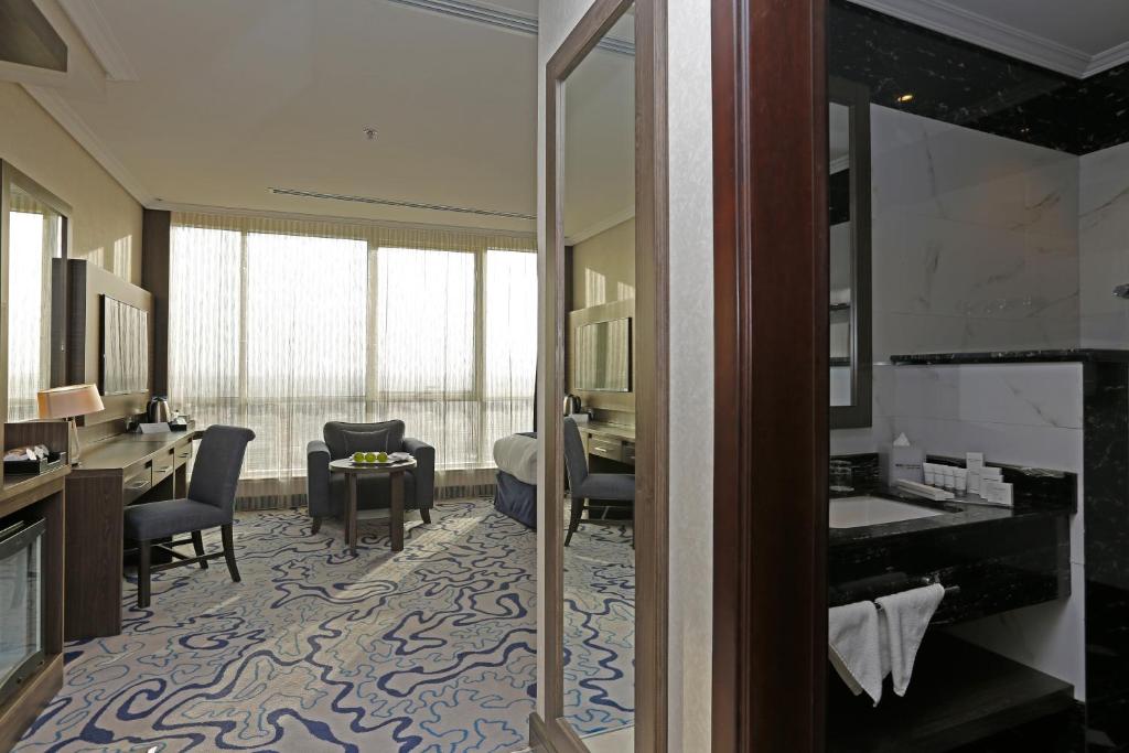 a bathroom with a sink and a desk in a room at Swiss Flora Royal Hotel Riyadh in Riyadh