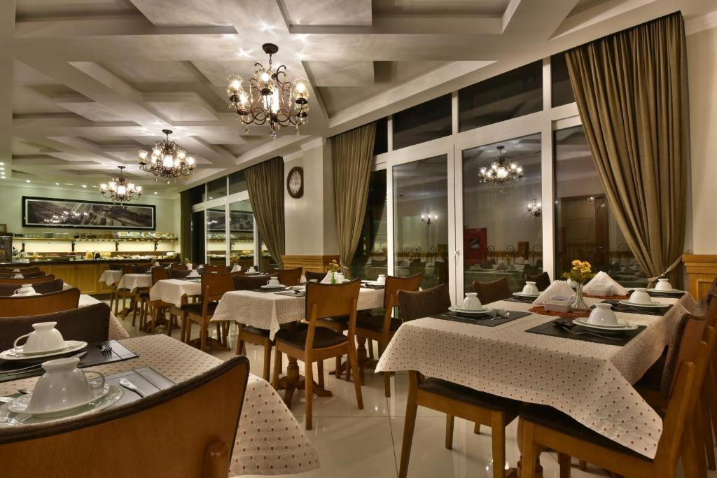 um restaurante com mesas e cadeiras e um lustre em Micheline Hotel Tricot - ao lado da Rua Coberta em Gramado